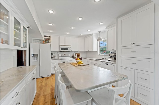 kitchen featuring light wood-type flooring, tasteful backsplash, pendant lighting, and white appliances