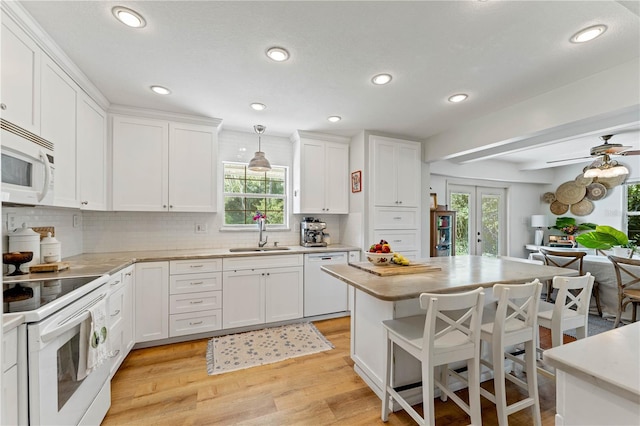 kitchen featuring light hardwood / wood-style flooring, tasteful backsplash, white cabinetry, sink, and white appliances