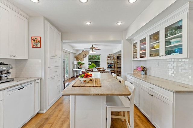 kitchen with white cabinetry, light hardwood / wood-style flooring, white dishwasher, tasteful backsplash, and ceiling fan