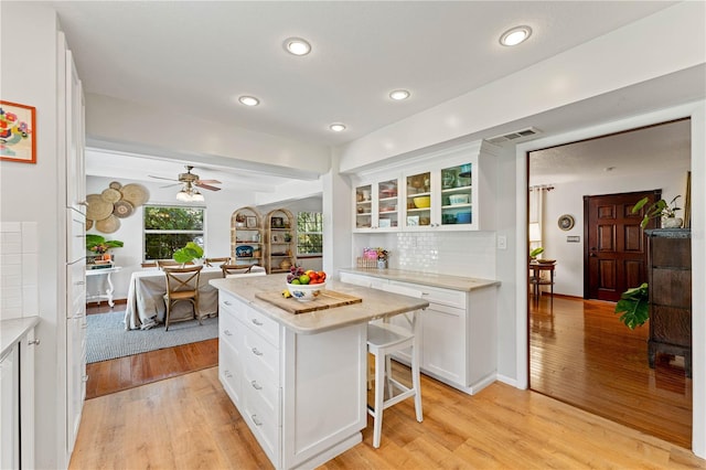 kitchen featuring light wood-type flooring, a kitchen bar, a center island, and tasteful backsplash