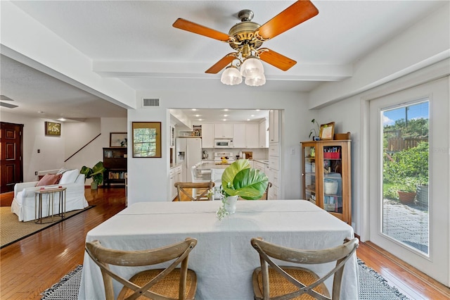 dining room featuring beam ceiling, ceiling fan, and light wood-type flooring