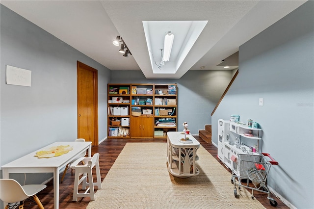 game room featuring rail lighting and dark hardwood / wood-style floors