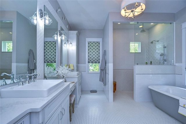 bathroom featuring vanity, tile patterned floors, tile walls, and a healthy amount of sunlight