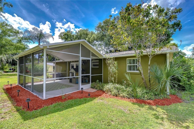 back of property with a yard, a patio area, and a sunroom