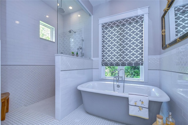 bathroom with tile patterned floors, plenty of natural light, independent shower and bath, and tile walls