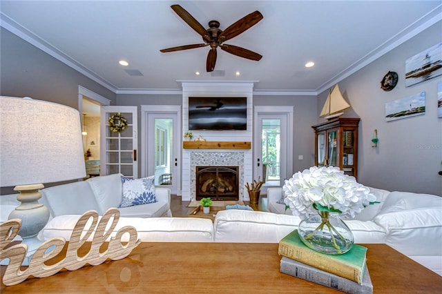 living room featuring a tile fireplace, ceiling fan, and ornamental molding