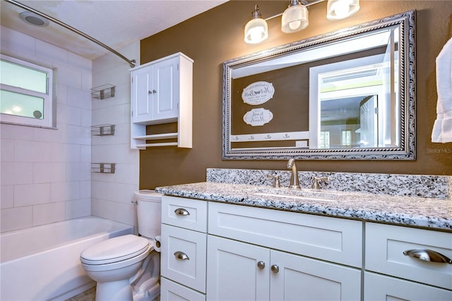 full bathroom with vanity, toilet, a textured ceiling, and tiled shower / bath combo