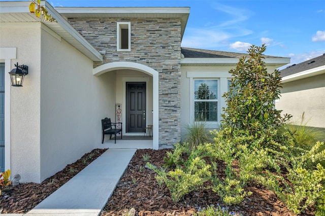 doorway to property with stone siding and stucco siding