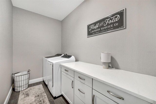 laundry room featuring cabinet space, washing machine and dryer, baseboards, and dark wood finished floors