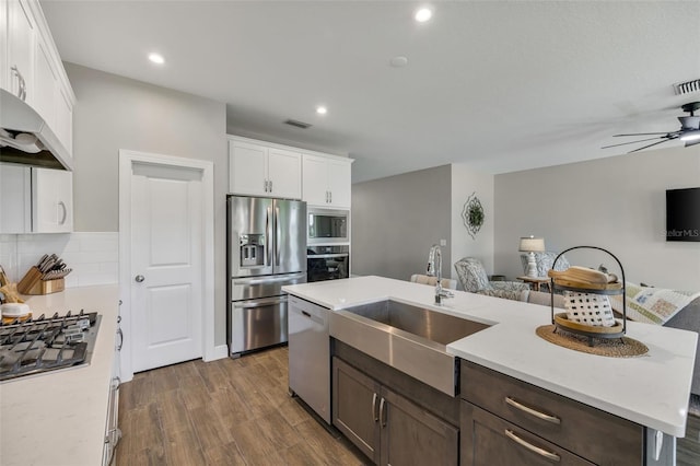 kitchen with a kitchen island with sink, sink, dark hardwood / wood-style flooring, white cabinetry, and stainless steel appliances