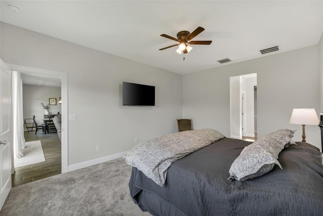 bedroom with light carpet, ceiling fan, visible vents, and baseboards