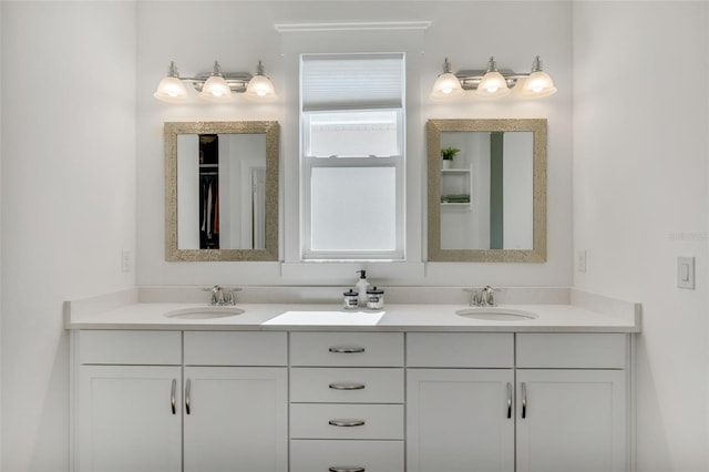 bathroom with double vanity, a sink, and a walk in closet