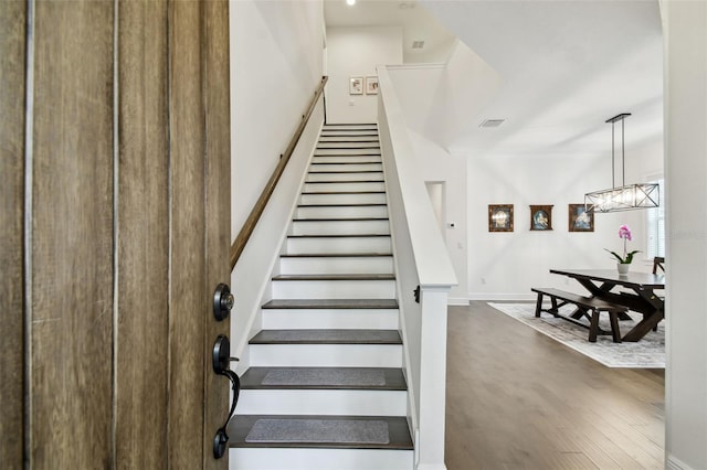 stairway with an inviting chandelier and wood-type flooring