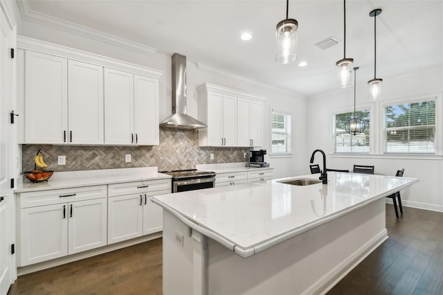 kitchen with white cabinetry, a center island with sink, hanging light fixtures, wall chimney range hood, and stainless steel electric stove