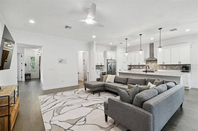 living room with crown molding, sink, dark hardwood / wood-style floors, and ceiling fan