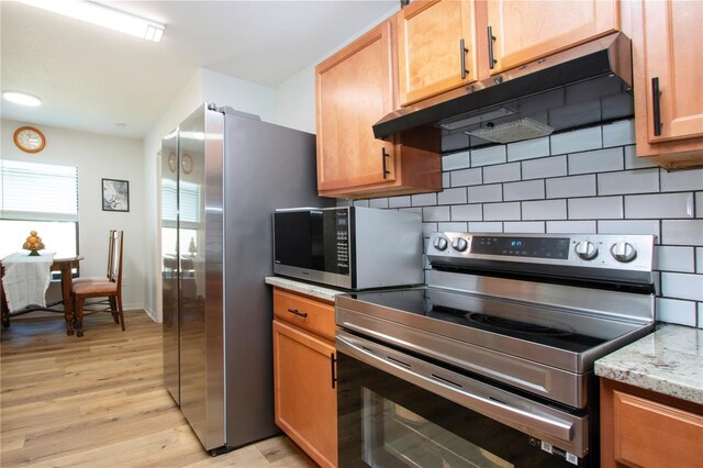 kitchen with stainless steel appliances, light hardwood / wood-style flooring, tasteful backsplash, and light stone countertops