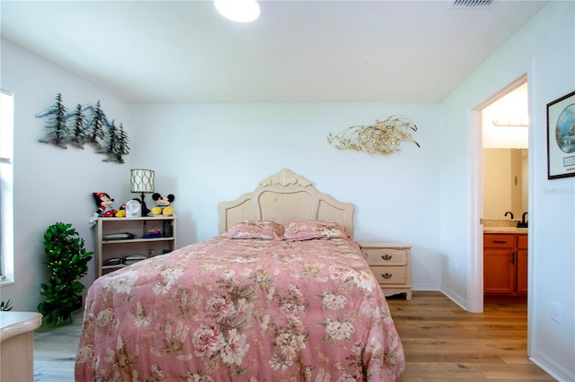 bedroom featuring light hardwood / wood-style floors and connected bathroom