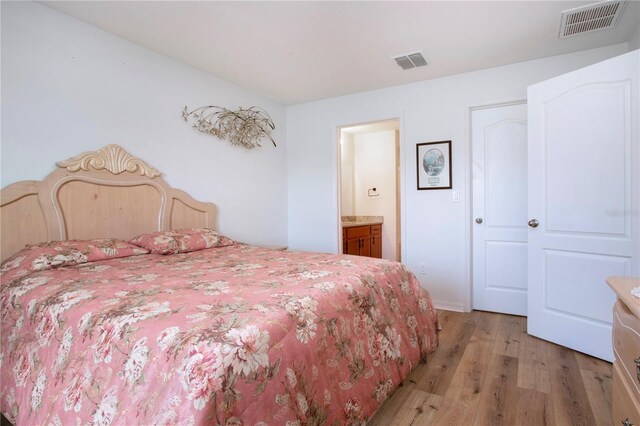 bedroom featuring light wood-type flooring and ensuite bath