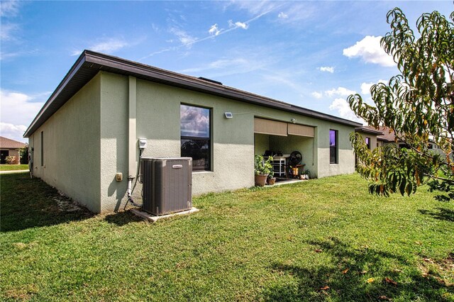 rear view of house with central air condition unit and a yard