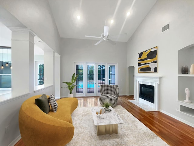 living area featuring visible vents, decorative columns, a premium fireplace, and wood finished floors