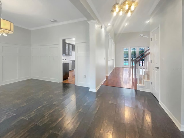 interior space with dark wood-style flooring, a decorative wall, stairway, and ornate columns