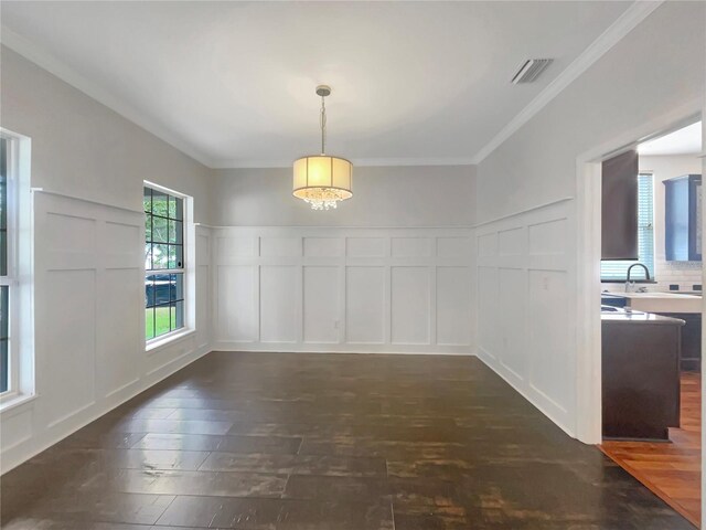 unfurnished dining area featuring sink, dark wood-type flooring, and ornamental molding