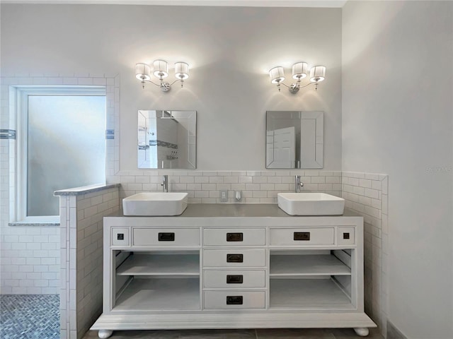 full bath with tiled shower, a sink, and double vanity