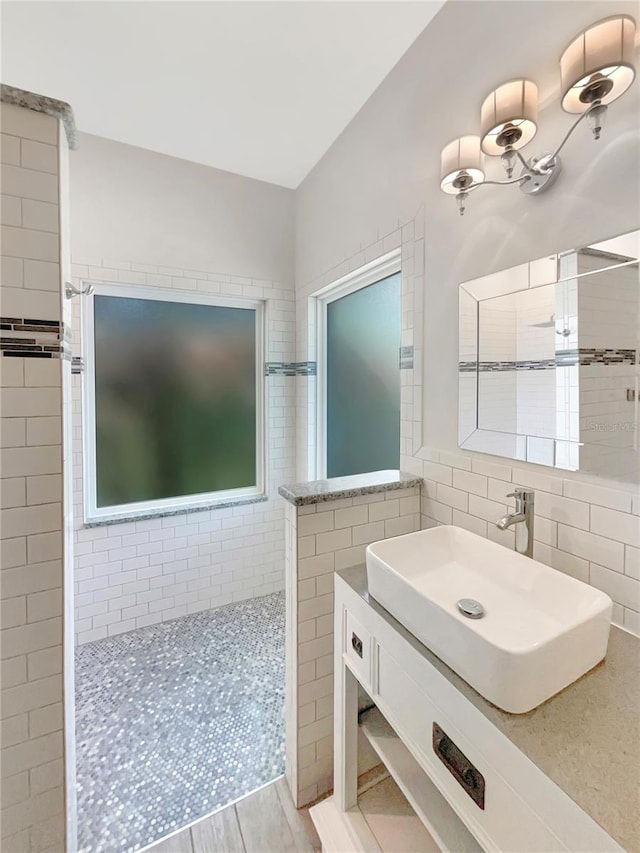 bathroom featuring tile walls, a walk in shower, and a sink