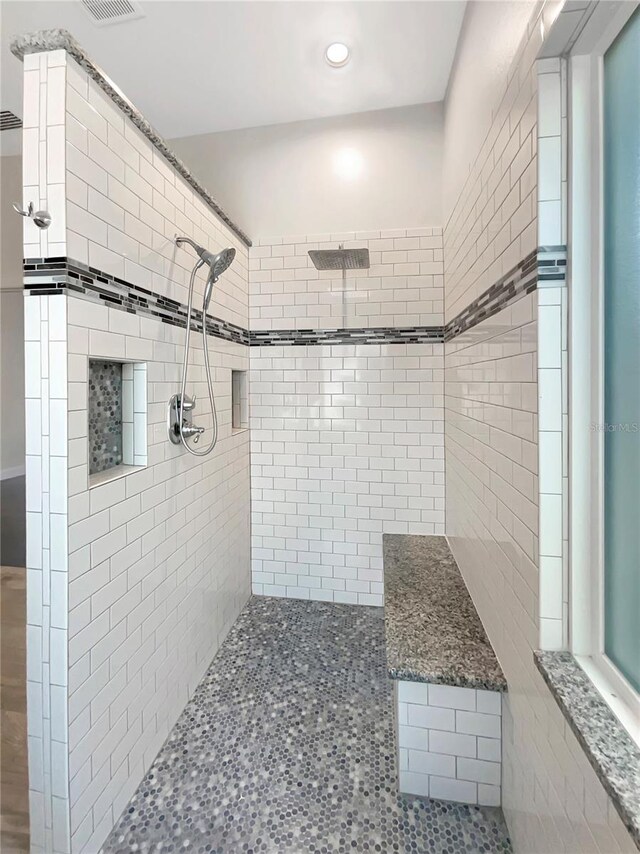 bathroom with tiled shower and visible vents