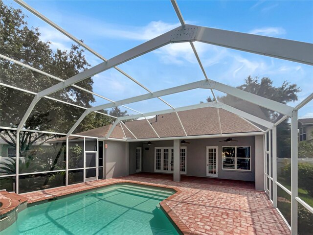 view of swimming pool featuring ceiling fan, glass enclosure, french doors, and a patio area