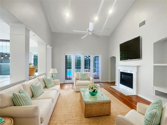 living area with light wood-type flooring, high vaulted ceiling, ceiling fan, and visible vents