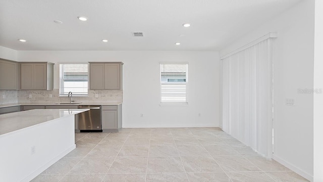 kitchen with sink, gray cabinets, dishwasher, light tile patterned flooring, and decorative backsplash