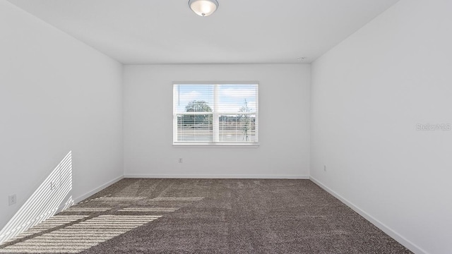 spare room featuring dark colored carpet