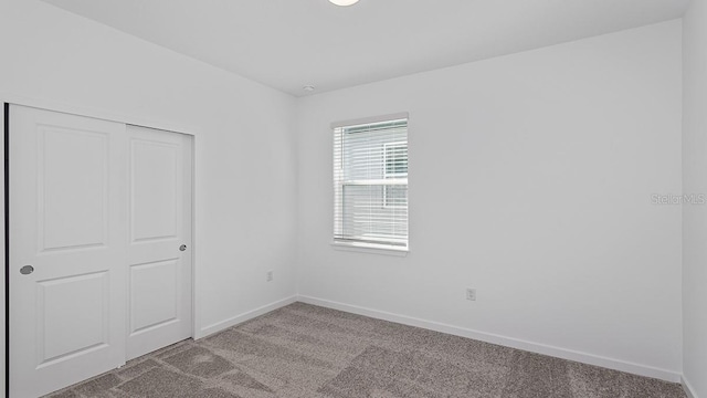 unfurnished bedroom featuring light colored carpet and a closet