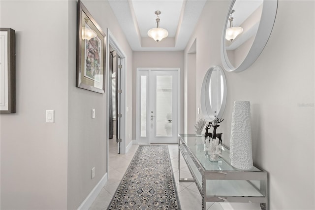 entryway featuring a raised ceiling and light tile patterned floors