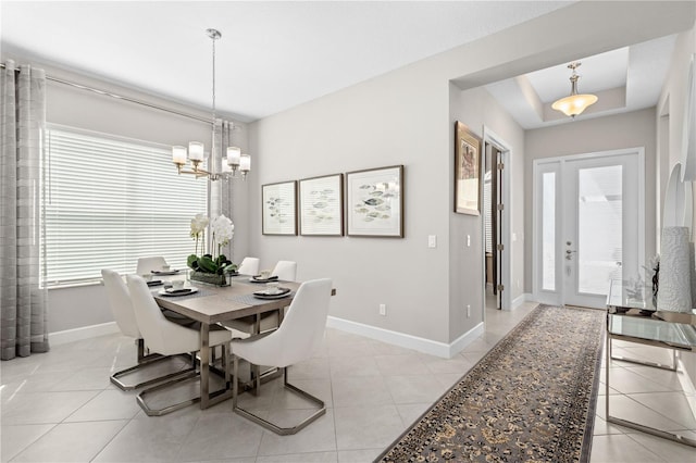 dining space with light tile patterned flooring, a raised ceiling, and a chandelier