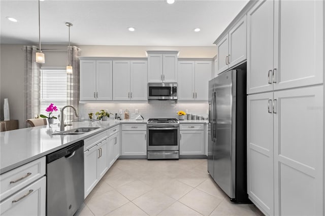 kitchen featuring backsplash, pendant lighting, appliances with stainless steel finishes, sink, and light tile patterned flooring