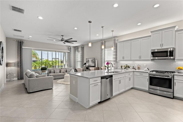 kitchen with appliances with stainless steel finishes, sink, kitchen peninsula, ceiling fan, and hanging light fixtures