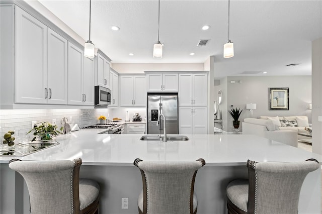 kitchen with backsplash, a breakfast bar area, appliances with stainless steel finishes, sink, and kitchen peninsula