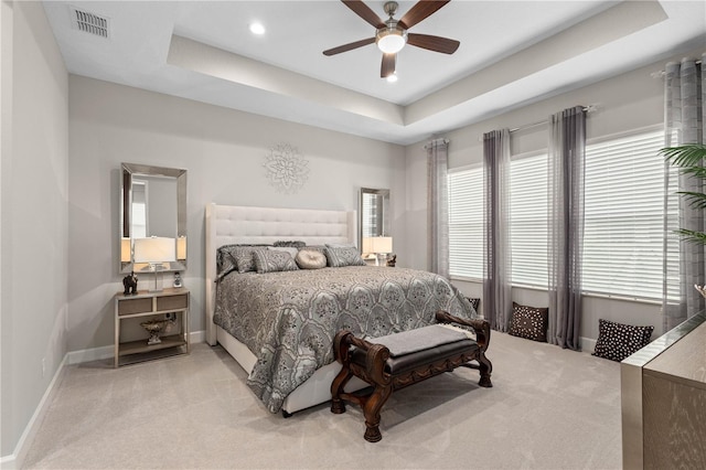 carpeted bedroom with ceiling fan and a raised ceiling