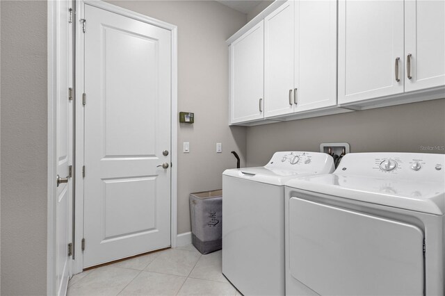 laundry room featuring light tile patterned floors, cabinets, and washer and clothes dryer