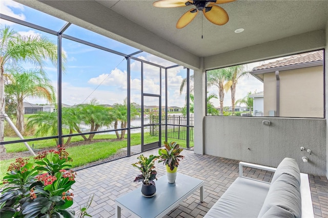 sunroom / solarium with ceiling fan and a water view