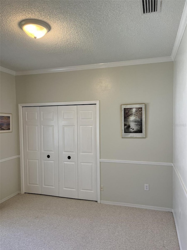 unfurnished bedroom featuring light carpet, a closet, ornamental molding, and a textured ceiling