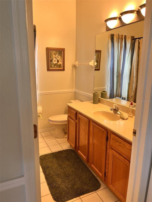 bathroom with toilet, vanity, and tile patterned flooring