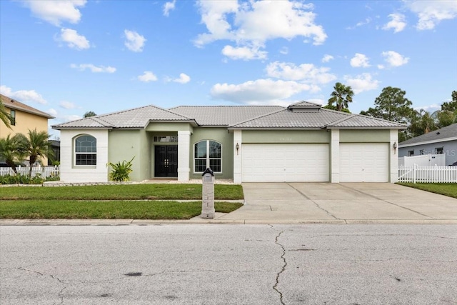 view of front of property with driveway, an attached garage, fence, a front yard, and stucco siding