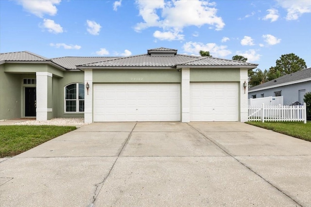 view of front of house with stucco siding, driveway, an attached garage, and fence