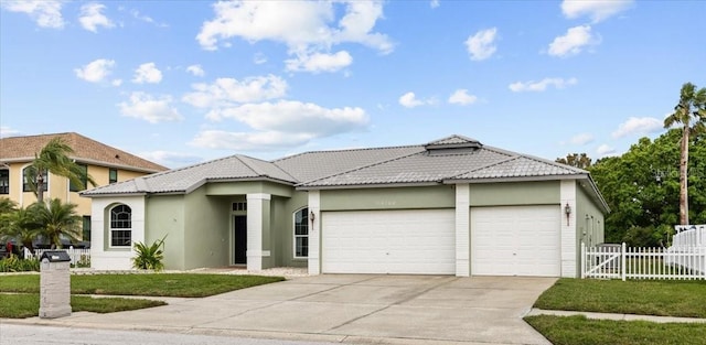 view of front of home with fence, a tiled roof, stucco siding, a garage, and driveway