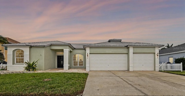 view of front facade with stucco siding, a front yard, fence, a garage, and concrete driveway