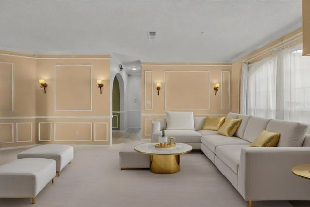 living area with arched walkways, a decorative wall, and visible vents