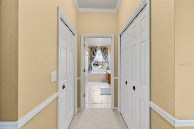 hall with light carpet, light tile patterned floors, baseboards, and ornamental molding